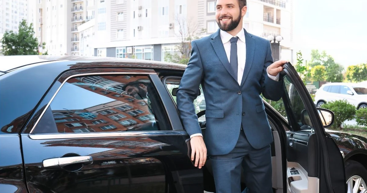 Chauffeurz Mercedes chauffeur completing a Birmingham Airport to London transfer, arriving at Mayfair luxury hotel with uniformed chauffeur handling luggage, premium door-to-door service