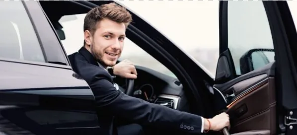 Professional London chauffeur in black suit at the wheel of an executive Mercedes, reserved for full-day private hire