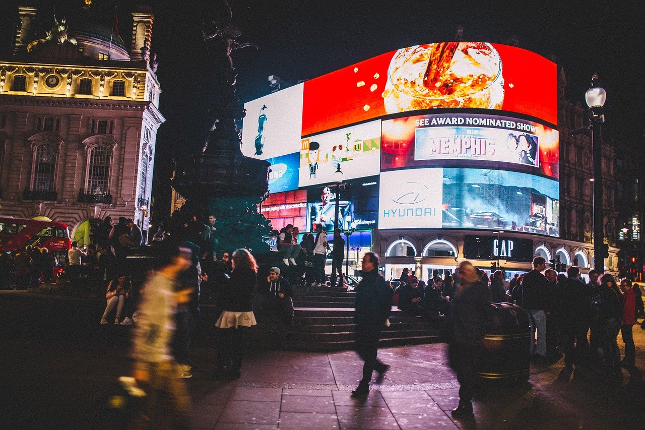 Piccadilly Circus at night with bright advertising lights on, surrounded by people and lively crowds, a vibrant part of the London night tour.