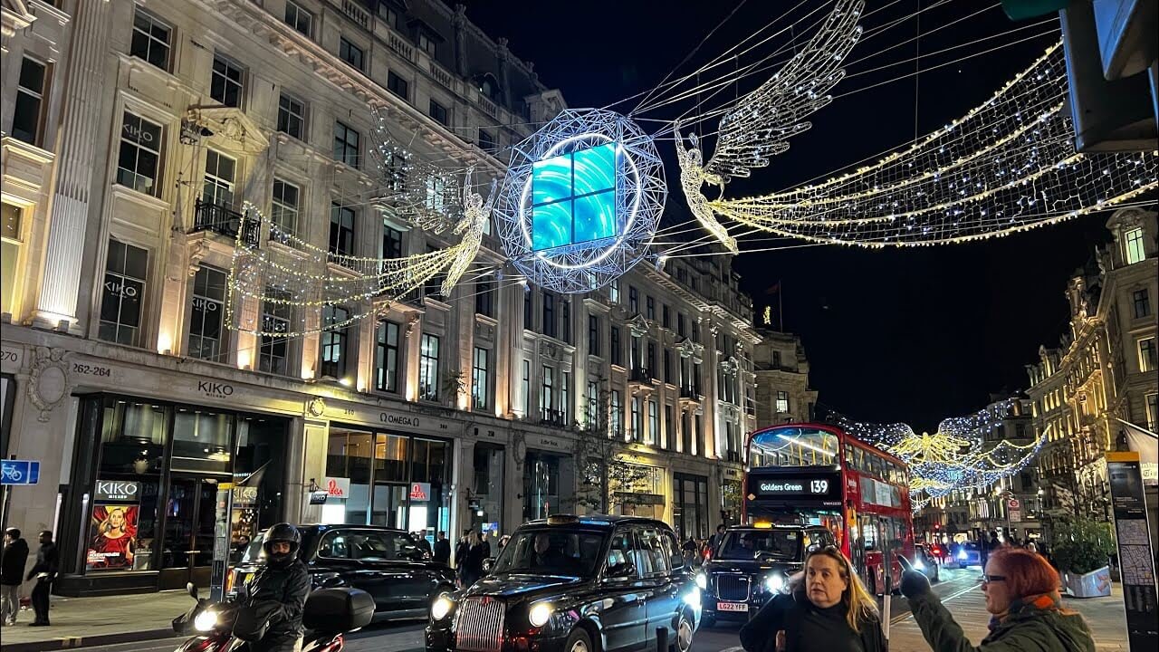 Regent Street by night during Christmas, decorated with illuminated angel lights, and people walking along the festive street in London.