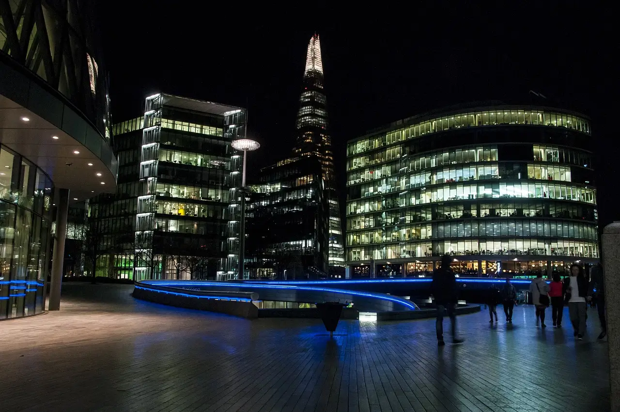 The Shard and surrounding buildings illuminated at night, reflecting beautifully in the River Thames during the London By Night Luxury Chauffeured Tour.