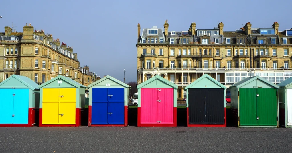 Colourful beach huts on the Brighton and Hove seafront with Regency buildings behind — Brighton private day tour from London with Chauffeurz